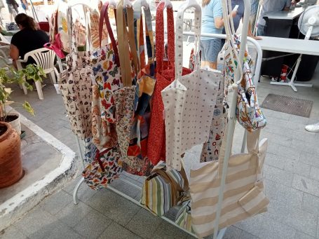 Variedad de bolsas de tela de colores y patrones colgadas en un soporte.