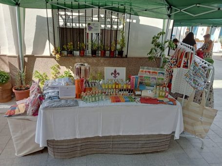 Mesa de mercado con productos artesanales bajo un toldo.